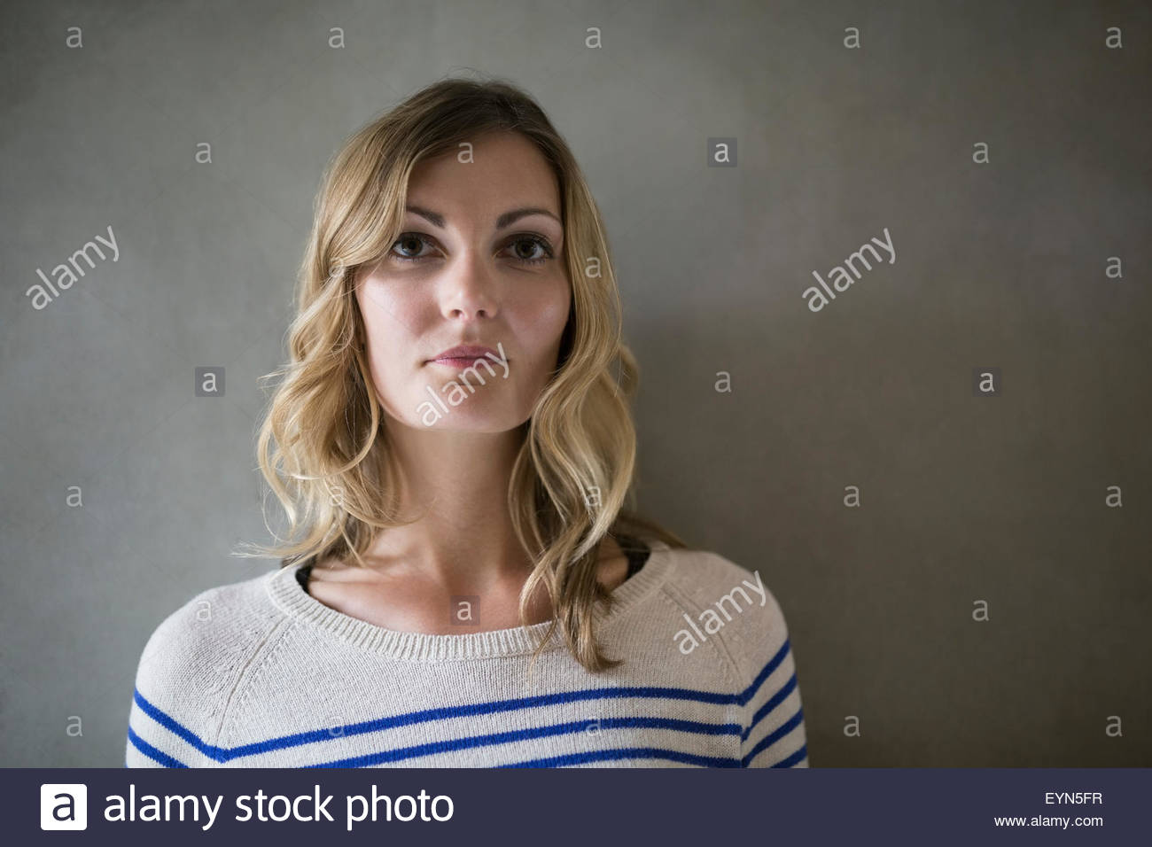 Porträt ernst blonde Frau vor grauem Hintergrund Stockfoto
