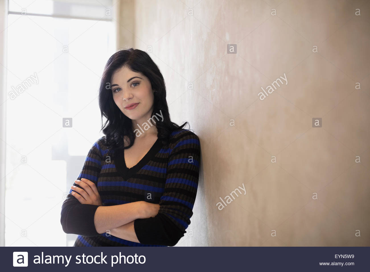 Porträt, selbstbewusste Frau mit Arme gekreuzten schiefen Wand Stockfoto