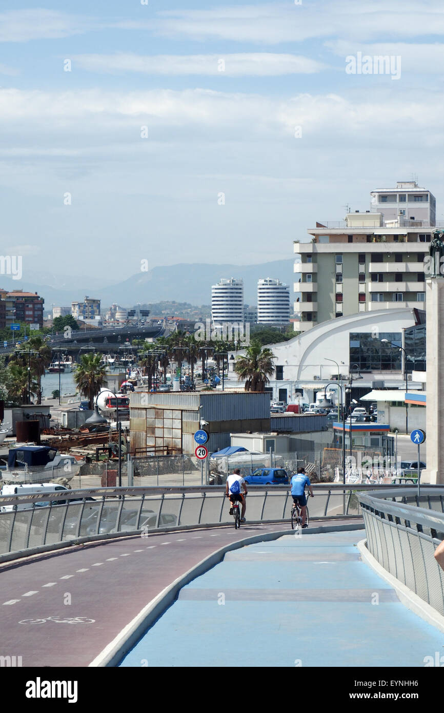 Zwei Radfahrer fahren auf der Ponte del Mare mit der Stadt Pescara im Hintergrund. Stockfoto