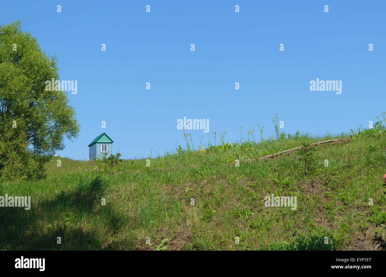 Einem einsamen Haus steht auf einem grünen Rasen-Hügel. Stockfoto
