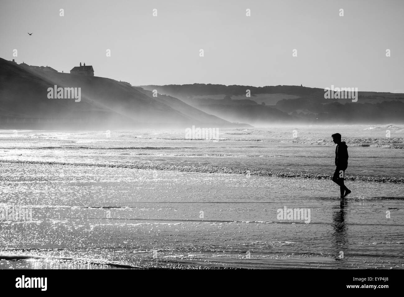 Eine einsame Gestalt auf Whitbys Strand wie ein Sommertag neigt sich dem Ende und Nebel rollt über den Hügeln von Whitbys. Stockfoto