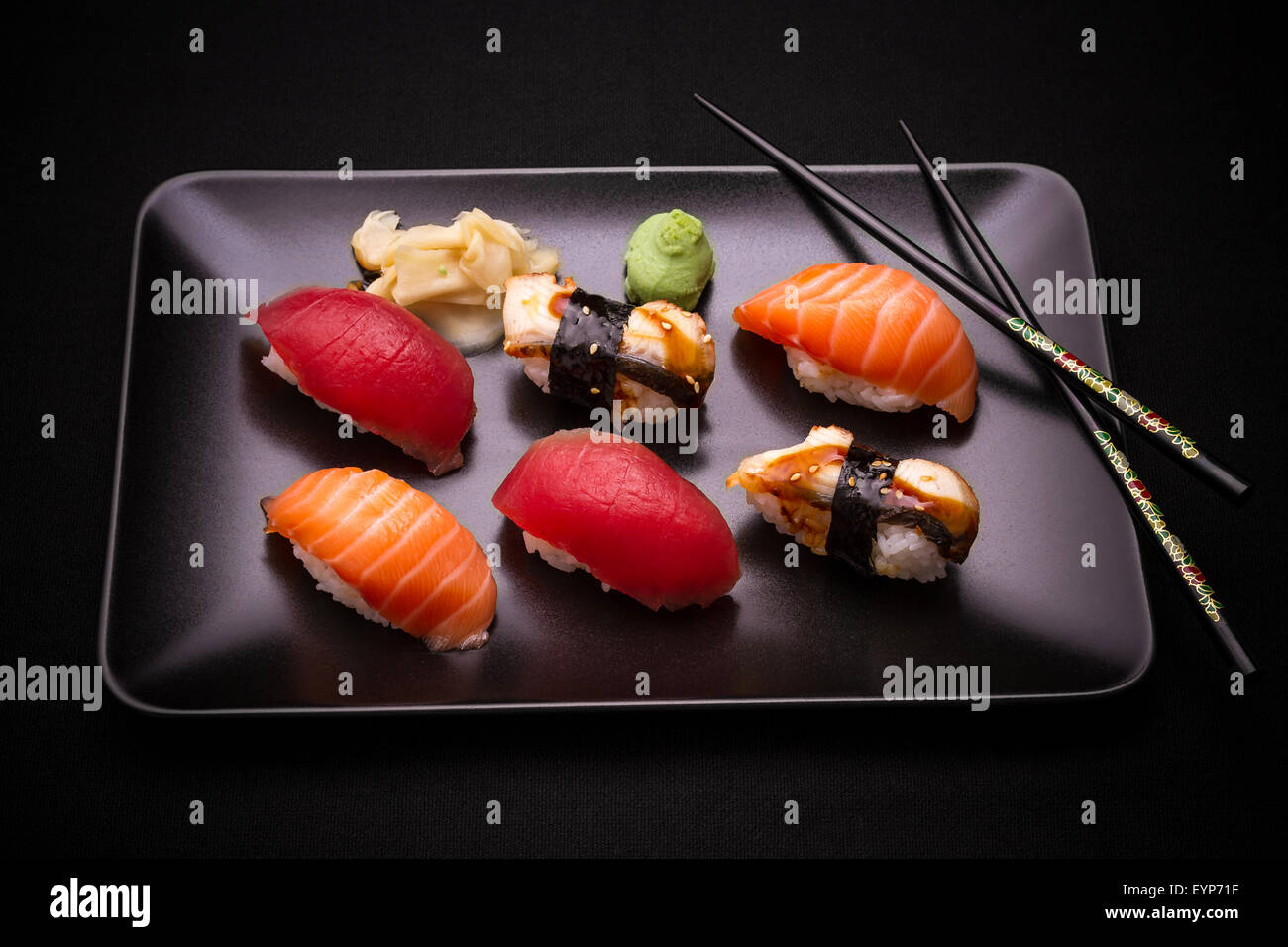 Aal, Lachs und Thunfisch-Sushi mit Stäbchen, dunklen Hintergrund, Ansicht von oben Stockfoto