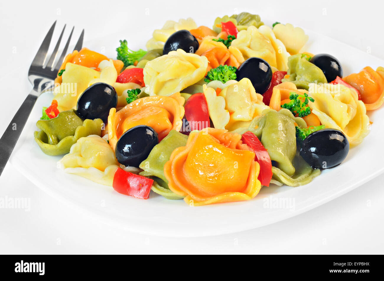 Salat mit Tortellini, Oliven, Brokkoli, rote Paprika, auf einem Teller, weiß-Hintergrund Stockfoto