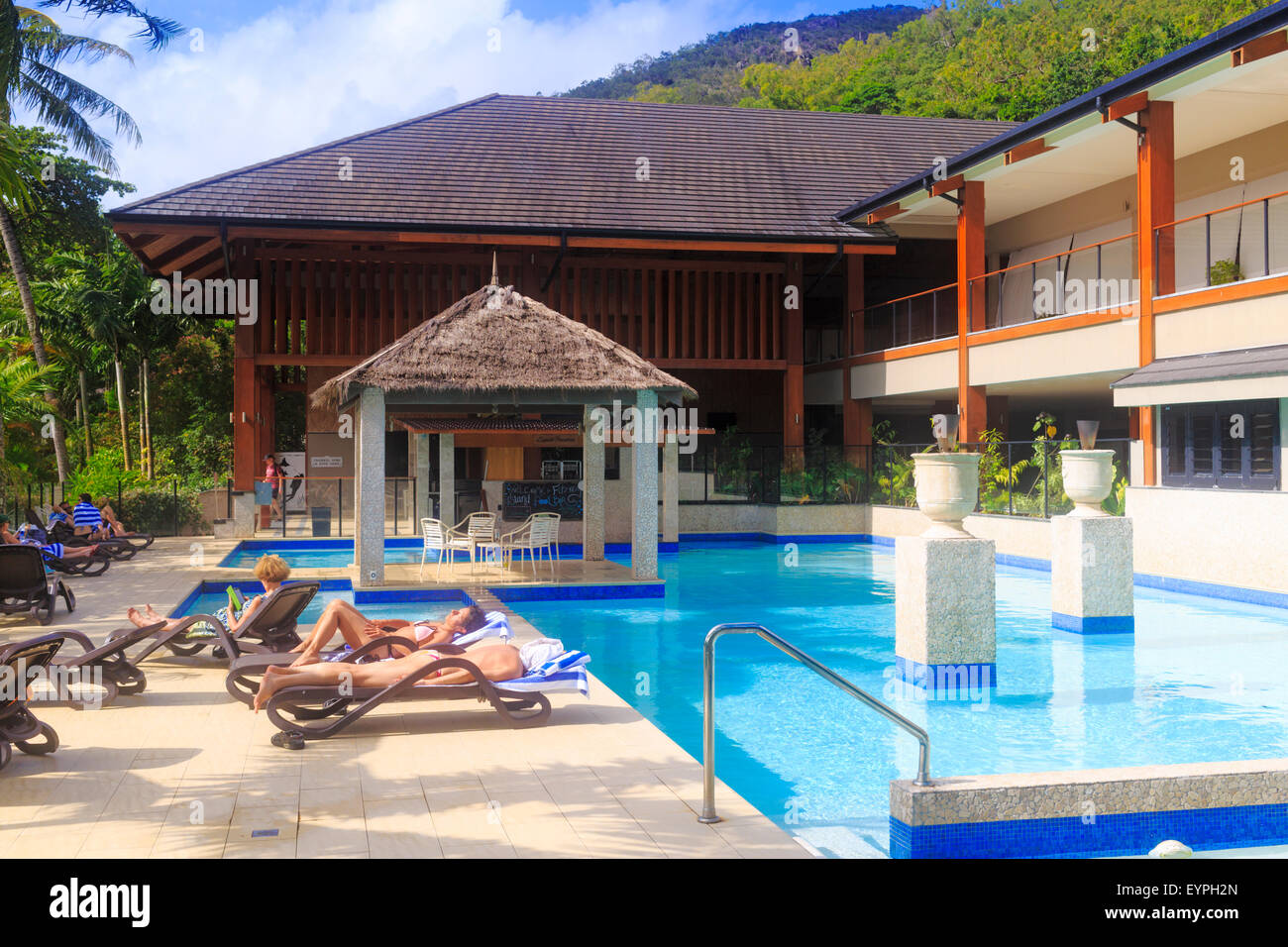 Menschen, die zum Sonnenbaden neben dem Schwimmbad im Fitzroy Island Resort, Queensland, Australien Stockfoto