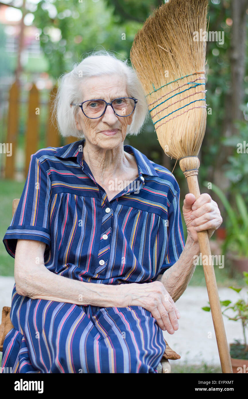 Alte Oma mit Besen von Hausarbeit ruhen Stockfoto