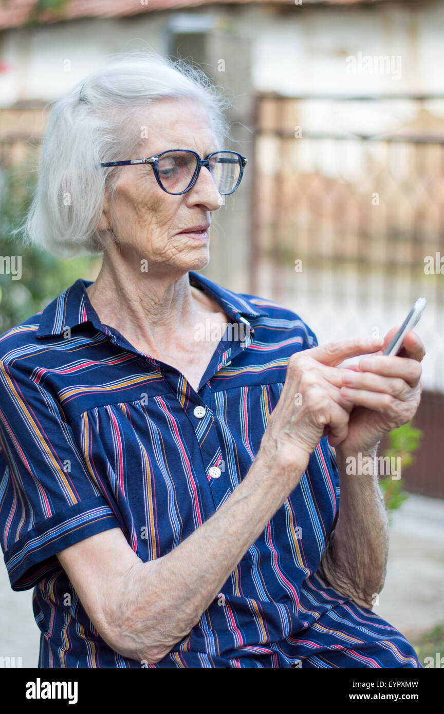 Alte Oma versucht, moderne Smartphone im Freien zu verwenden Stockfoto