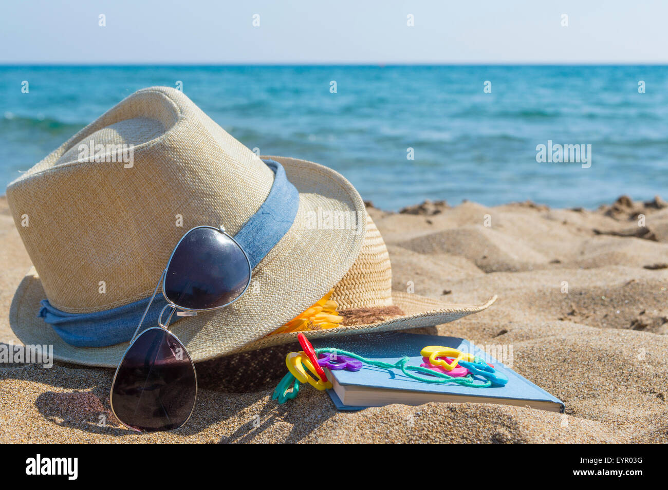 Stroh Sommerhüte, Sonnenbrillen und ein Buch am Strand. Sommer Urlaub Zubehör Stockfoto