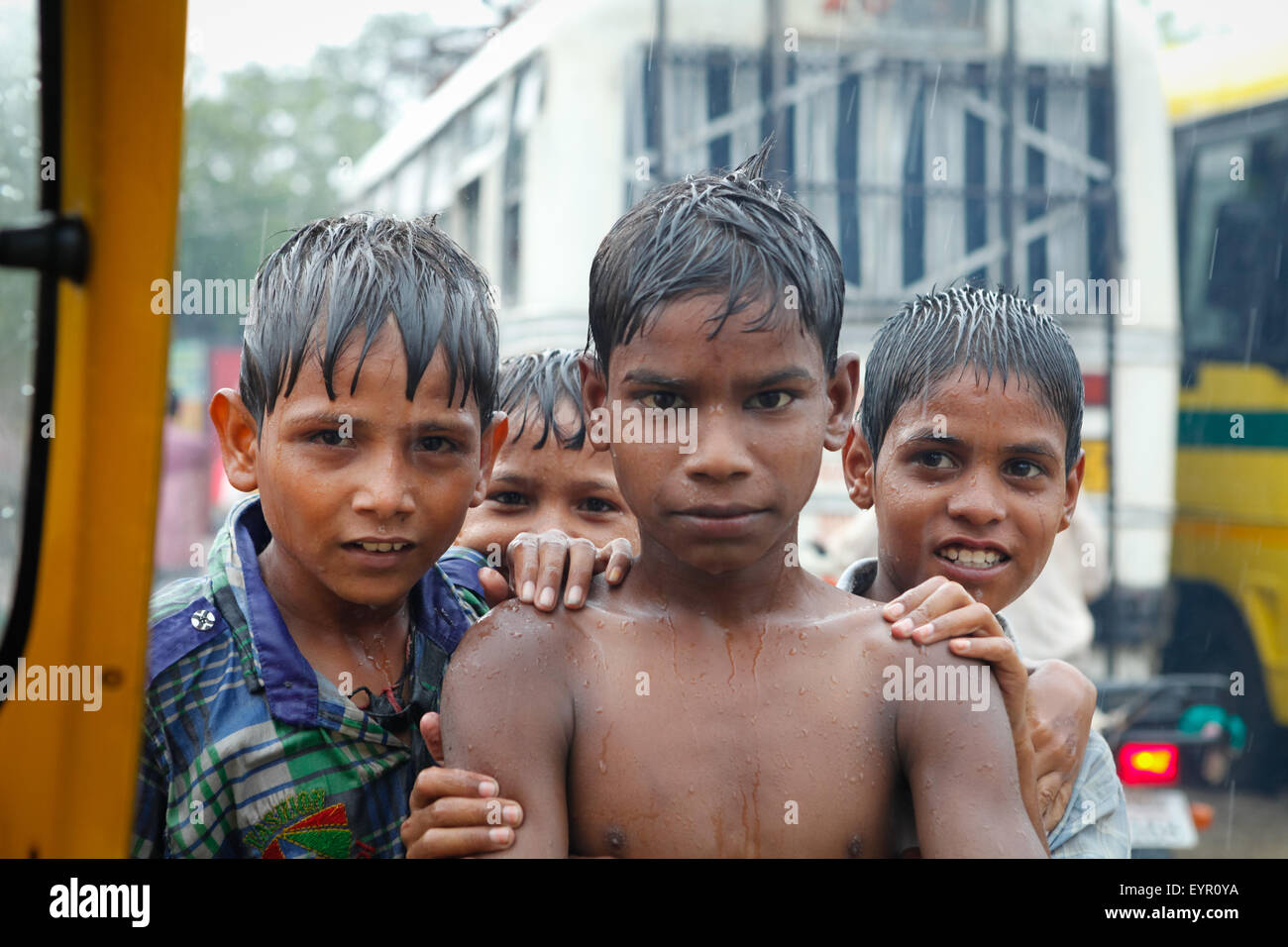 Porträt von Kindern, die während regnerischer Tage auf einer belebten Straße im indischen Uttar Pradesh im Regen spielen. Stockfoto