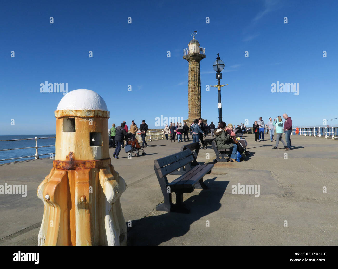 Touristen genießen die Frühlingssonne auf die beliebte Whitby West Pier. Stockfoto