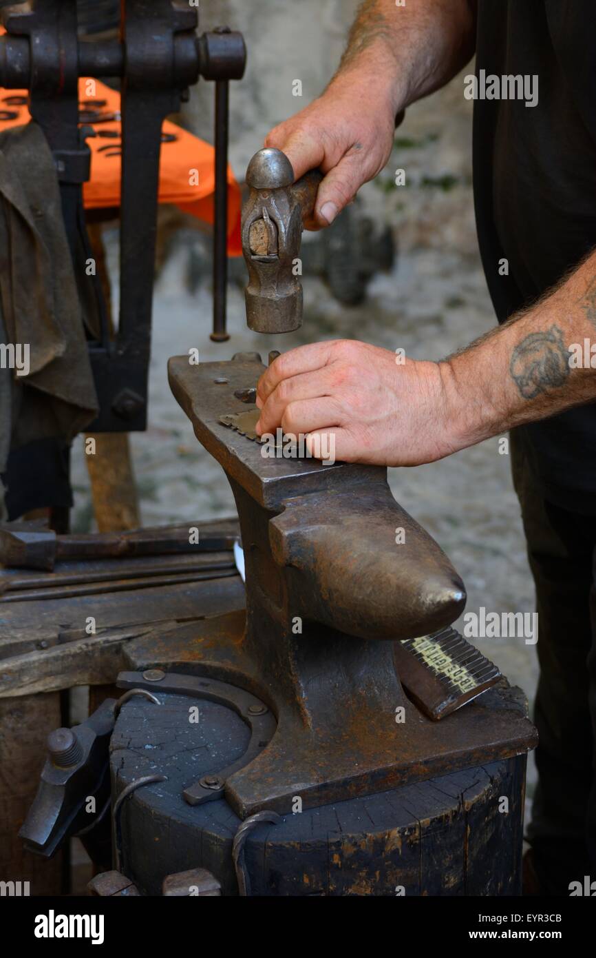 Schmied, der mit einem Hammer und Amboss auf heissem Metall auf einer mittelalterlichen Straßenmesse in der Altstadt von Ibiza, Spanien, arbeitet Stockfoto