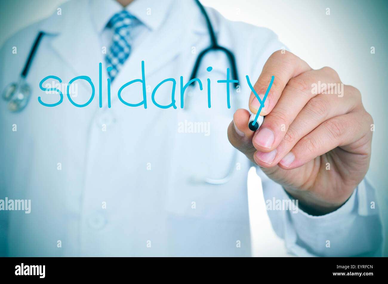 closeup of a young doctor writing the word solidarity in the foreground, for the concept of medical solidarity and aid Stockfoto