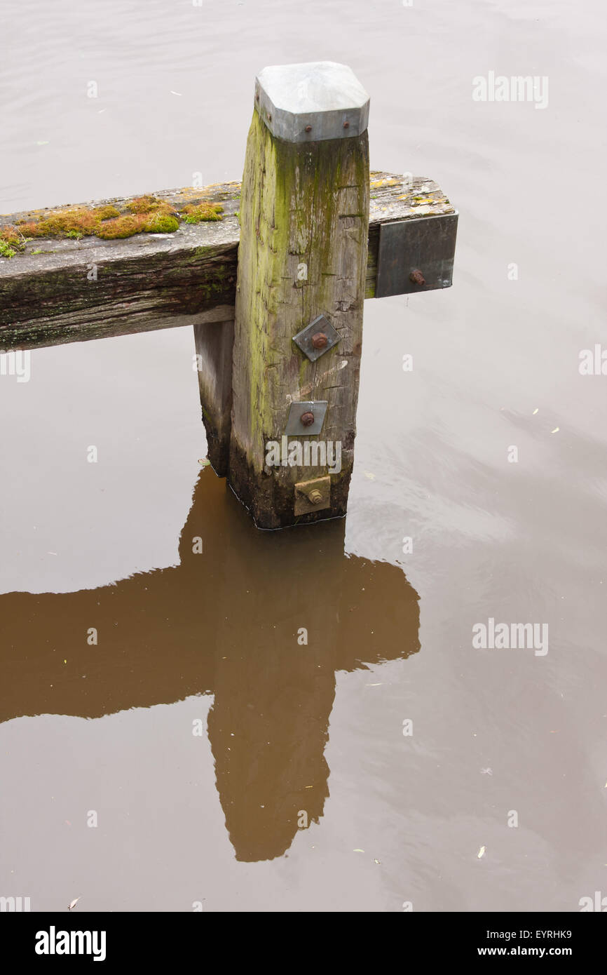 Alten verwitterten Poller mit einer Spiegelung im Wasser Stockfoto