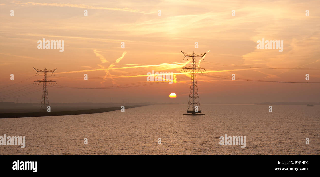 Sonnenaufgang über dem niederländischen Meer mit der Silhouette der beiden Strommasten Stockfoto