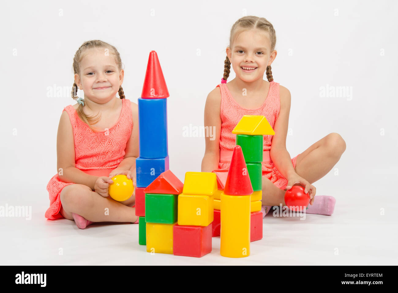 Die vier Jahre und sechs - jähriges Mädchen spielen in einem europäisch anmutenden Würfel, isoliert auf einem hellen Hintergrund Stockfoto