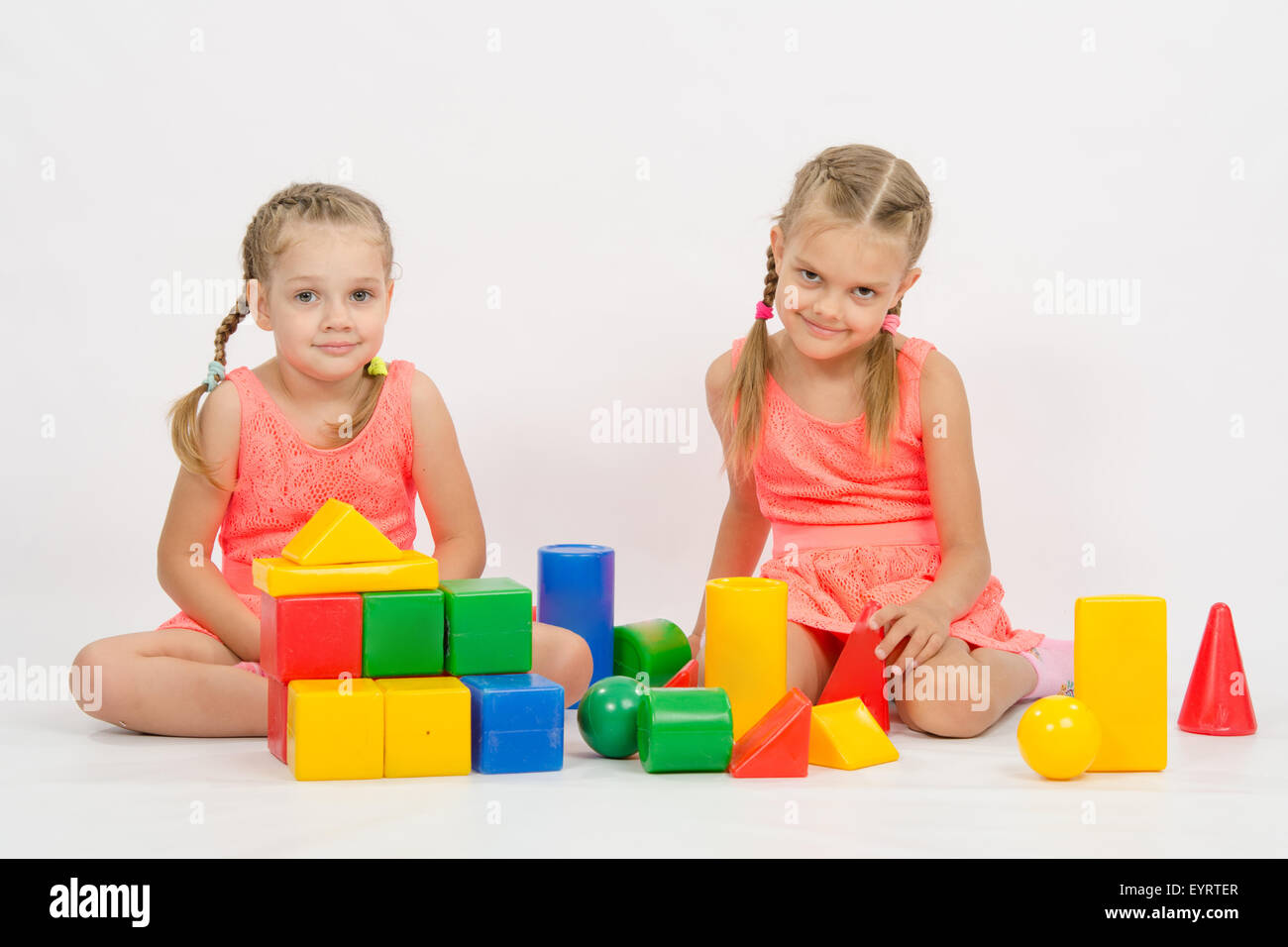Die vier Jahre und sechs - jähriges Mädchen spielen in einem europäisch anmutenden Würfel, isoliert auf einem hellen Hintergrund Stockfoto