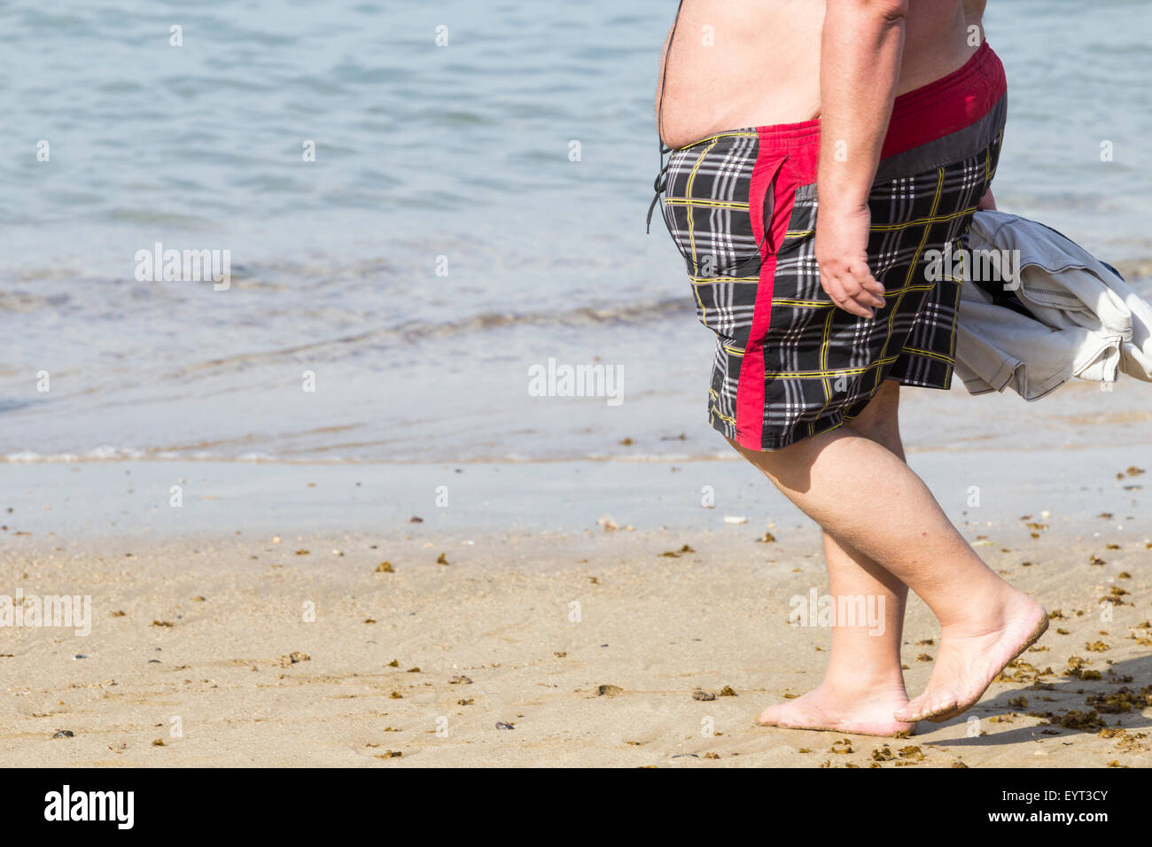 Übergewichtigen Mann zu Fuß am Strand Stockfoto