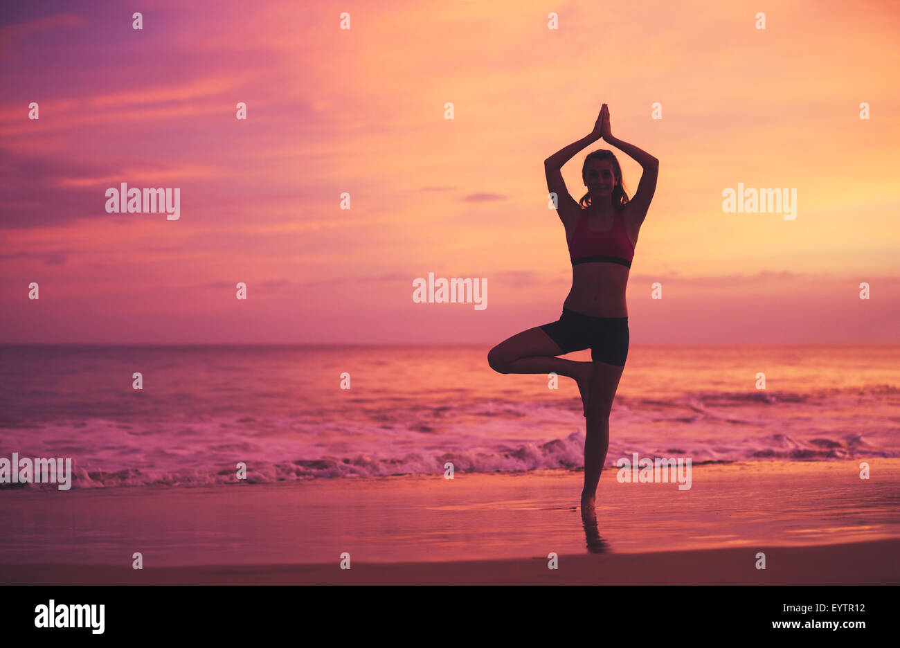 Silhouette der jungen Frau praktizieren Yoga am Strand bei Sonnenuntergang. Gesunden, aktiven Lebensstil. Stockfoto