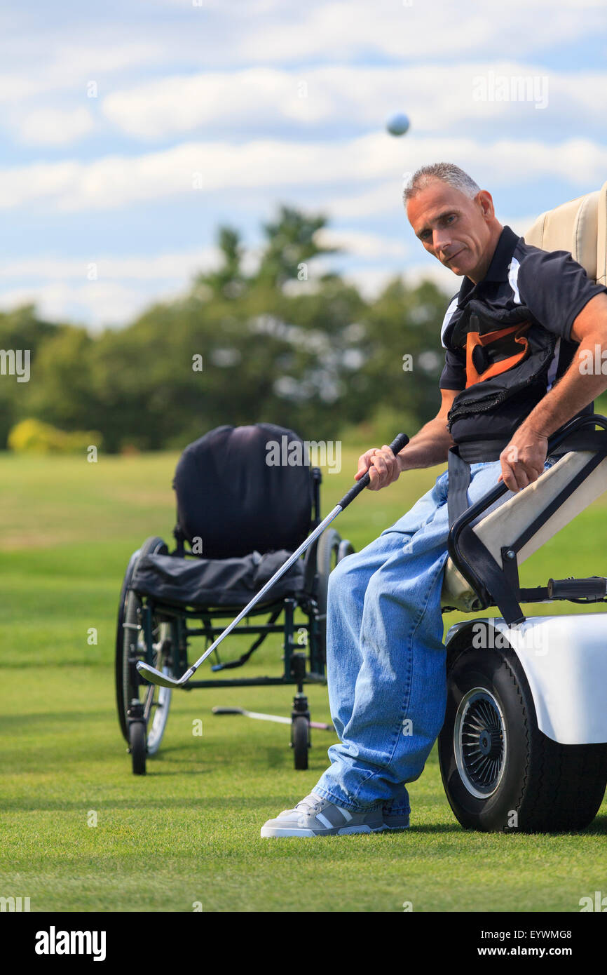 Mann mit einer Rückenmarksverletzung in eine adaptive Warenkorb zum Golfspielen Stockfoto