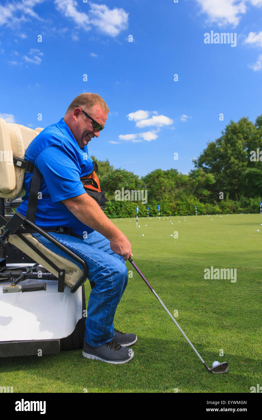 Mann mit einer Rückenmarksverletzung in eine adaptive Warenkorb bei Golf-Putting-green Stockfoto