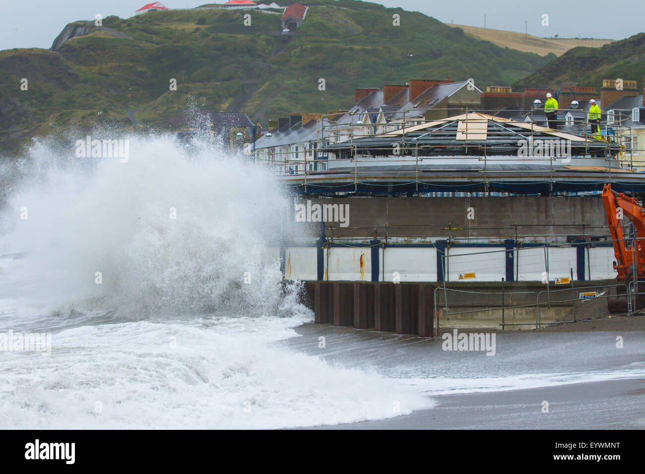 Aberystwyth, Wales, UK. 4. August 2015. Stürmisches Wetter. Eine 5-8 ft-Dünung, starke Winde und eine Flut Cmbine, Aberystwyth direkt am Meer mit riesigen Wellen, Peitschen, wie Arbeiter weiter arbeiten an der Strandpromenade der Musikpavillon Credit saniert: Alan Hale/Alamy Live News Stockfoto