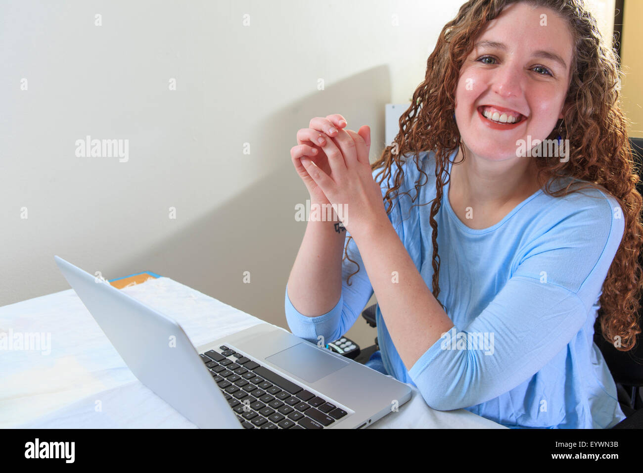 Frau mit Muskeldystrophie, die Arbeiten an ihrem Laptop in ihrem Büro Stockfoto