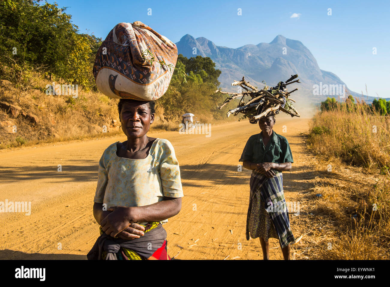 Einheimische Frauen tragen ihre waren auf ihren Köpfen vor Mount Mulanje, Malawi, Afrika Stockfoto