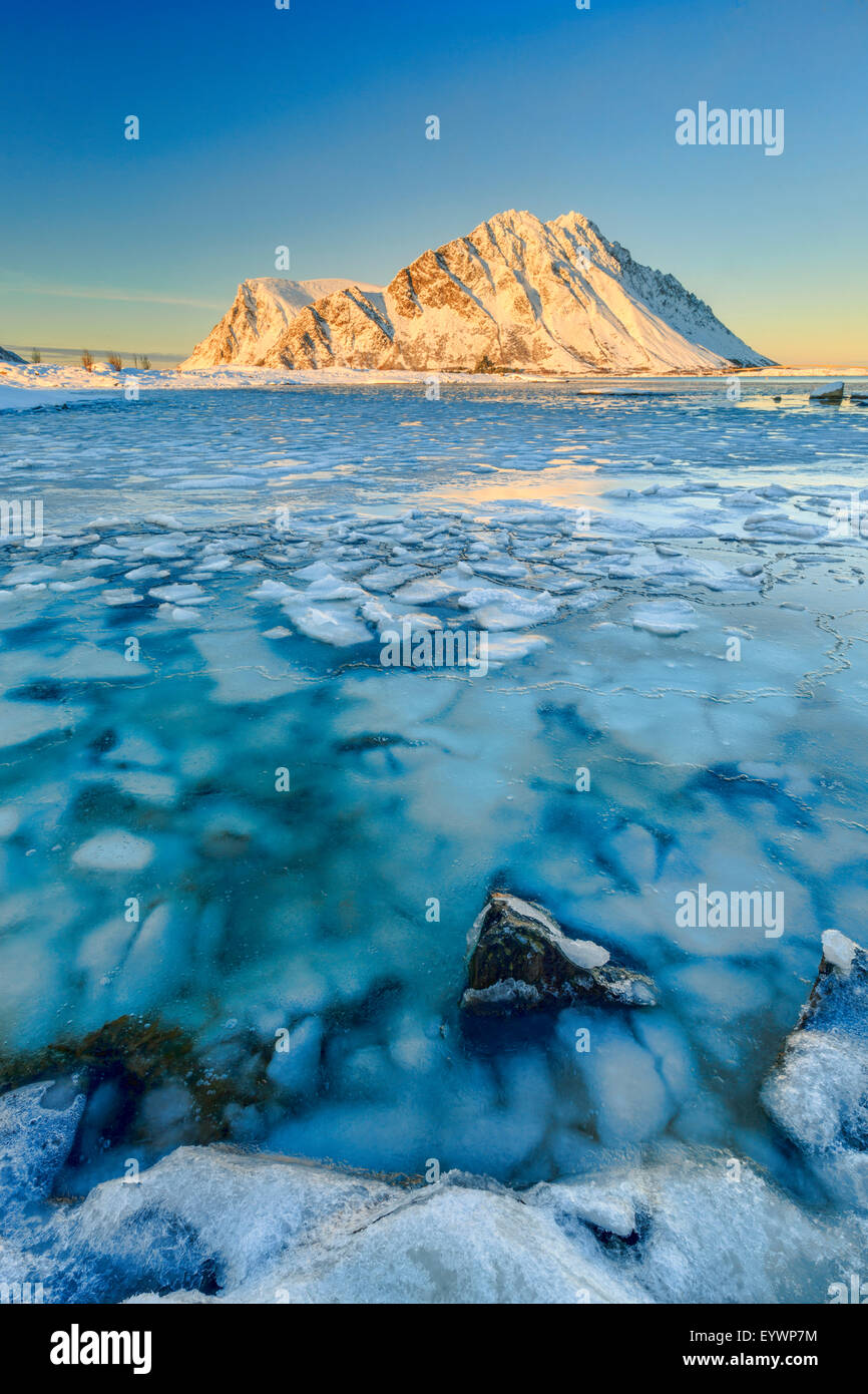 Berge von Gymsoya (Gimsoya) aus Smorten spiegelt sich im kristallklaren Meer noch teilweise gefroren, Lofoten-Inseln, Arktis, Norwegen Stockfoto