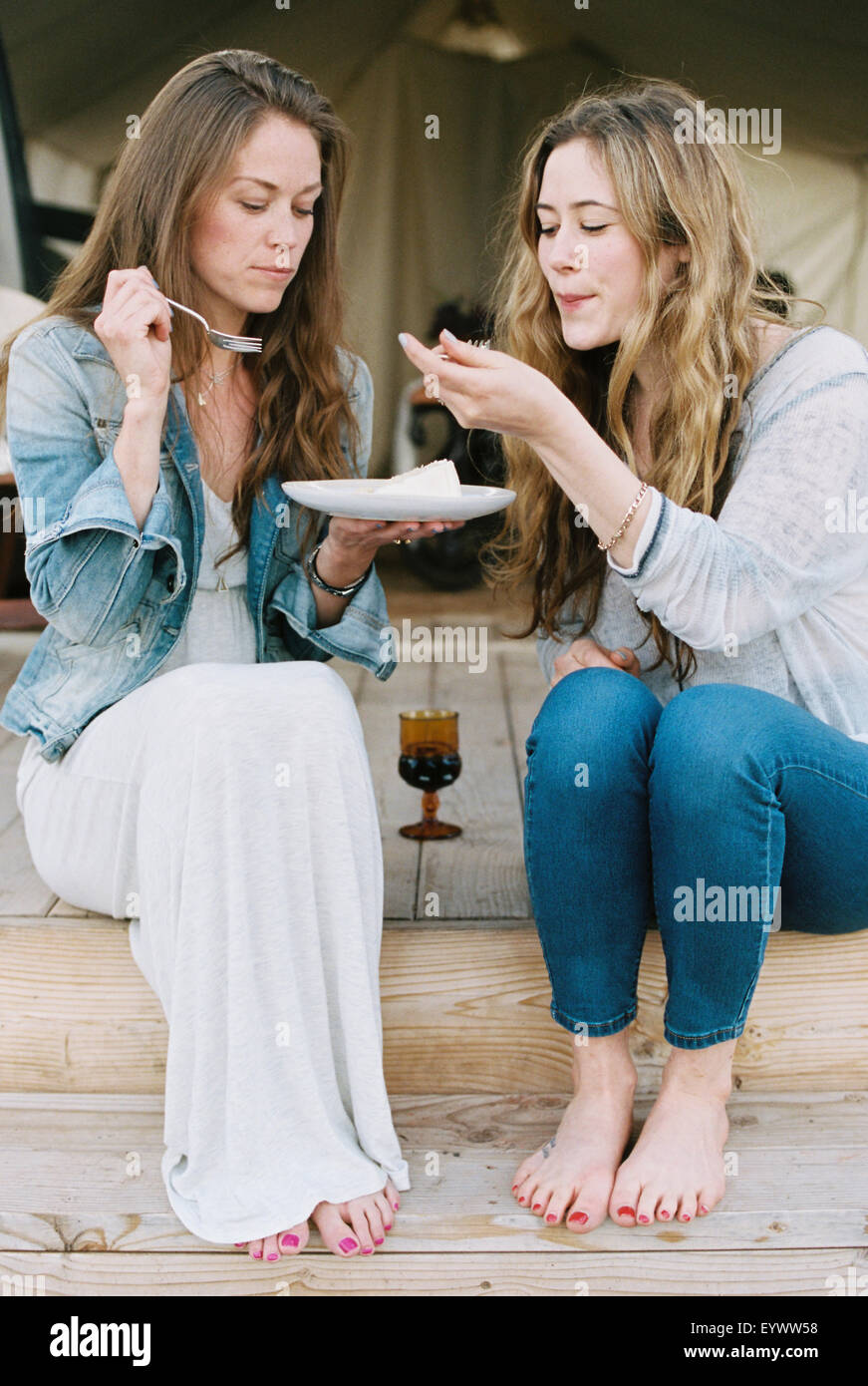 Zwei Frauen sitzen im Freien, Austausch von Kuchen und einem Glas Wein. Stockfoto