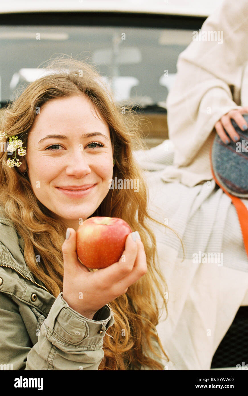 Eine junge Frau hält einen enthäuteten roten Apfel. Stockfoto