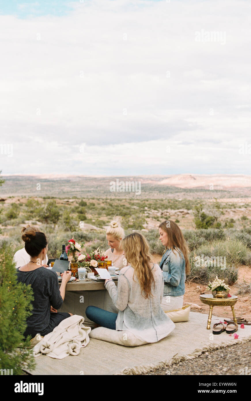 Eine Gruppe von Frauen, Rundtisch Freunde sitzen auf dem Boden in der offenen Wüste. Stockfoto
