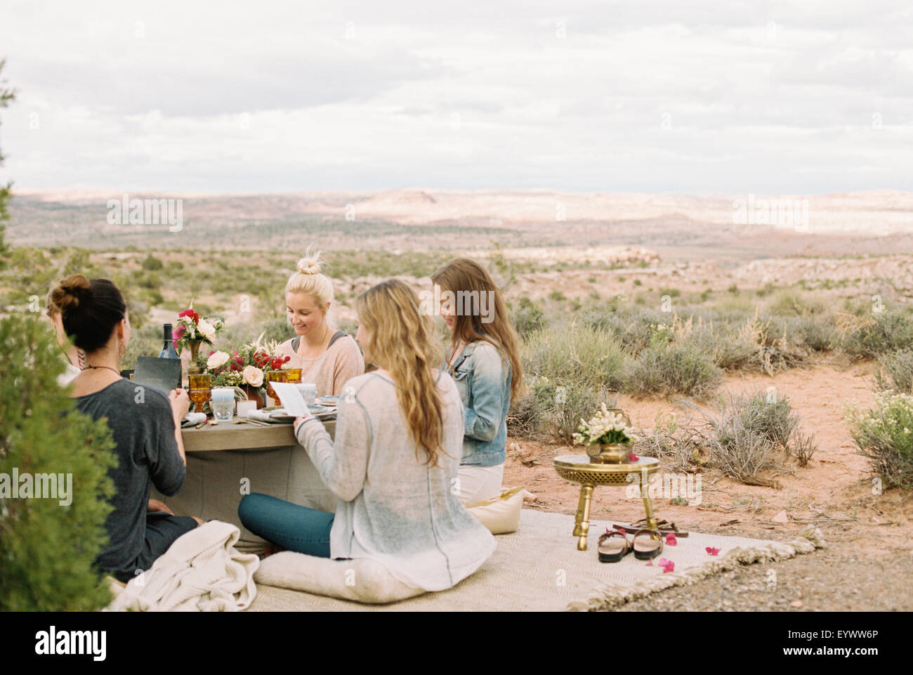 Eine Gruppe von Frauen, Runde Freunde sitzen auf dem Boden eine Tabelle mit einer Mahlzeit. Stockfoto