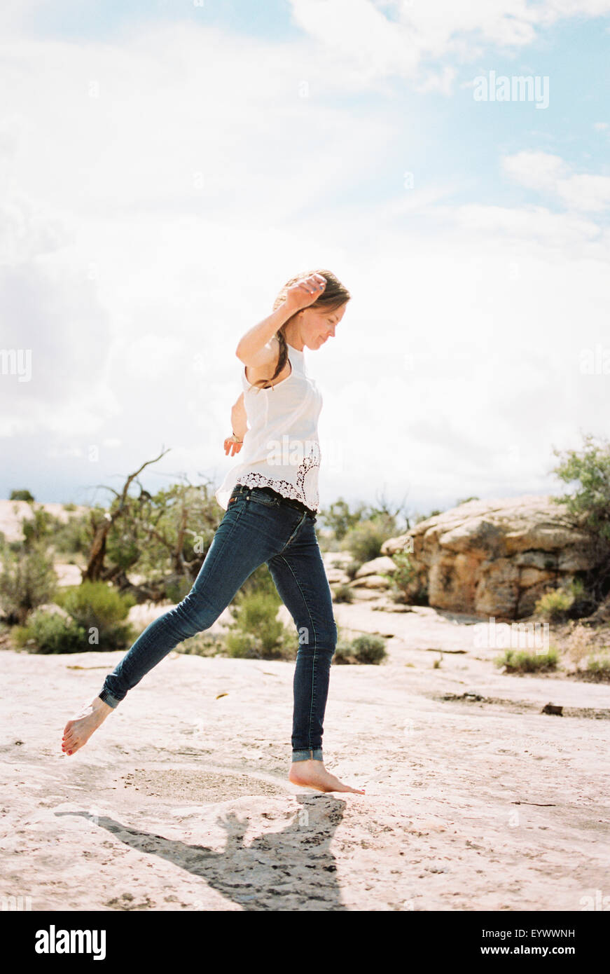 Eine Frau trägt Jeans tanzen in die Wüste. Stockfoto