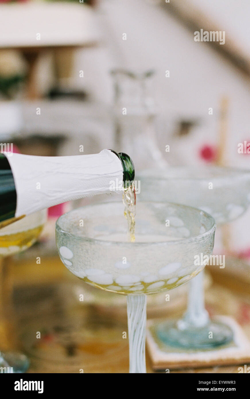 Champagner aus der Flasche in ein Glas gegossen wird. Stockfoto