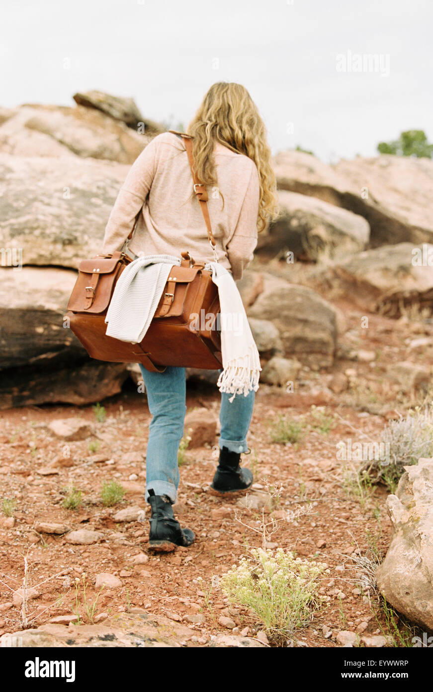 Frau zu Fuß in einer Wüste mit einer Ledertasche. Stockfoto
