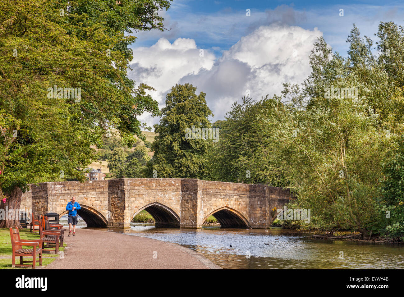 Ein Mann auf der Suche auf seine Uhr, als er neben dem Fluss Wye Spaziergänge, gebaut vor 5 Bogenbrücke vor 700 Jahren Bakewell, Derbyshire... Stockfoto