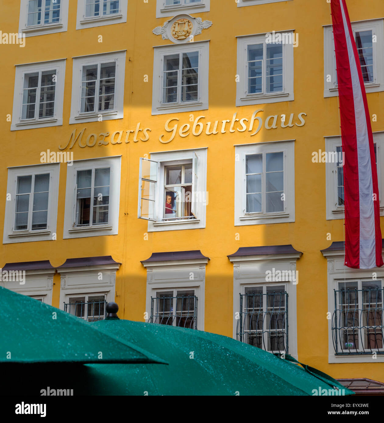 Salzburg, Salzburger Land, Österreich.  Mozarts Geburtshaus, mit einem Porträt des Komponisten durch ein Fenster sichtbar. Stockfoto