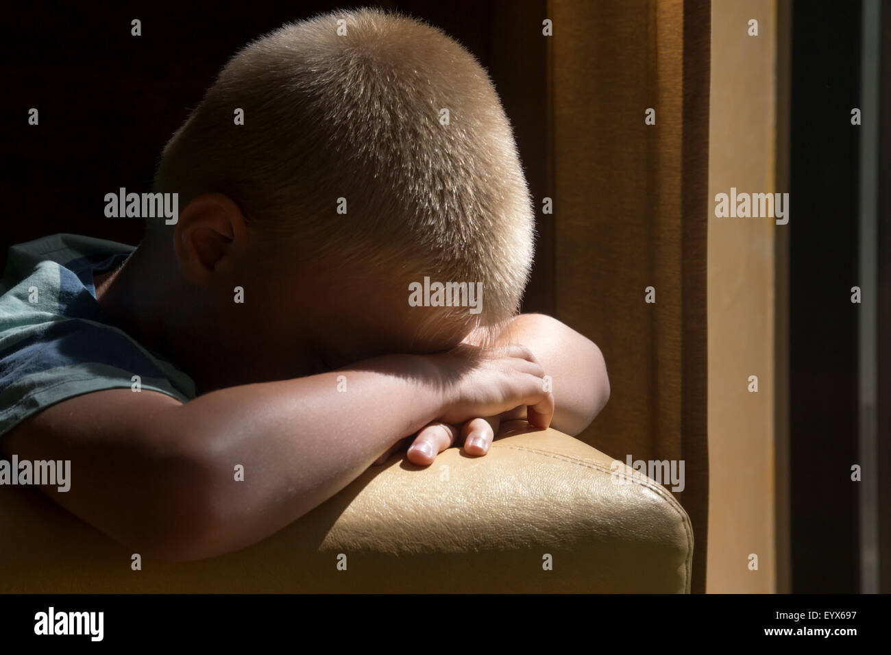 Kind (junge) in der Nähe eines Fensters depressiv traurig aufgeregt warten langweilig Stockfoto