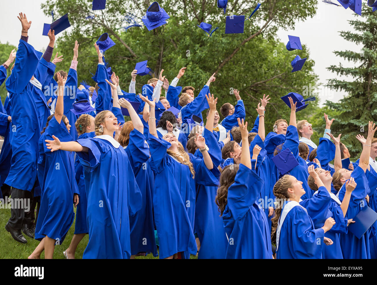 Absolventen, die Kappen in der Luft, in einer Highschool Abschlussfeier werfen. Stockfoto