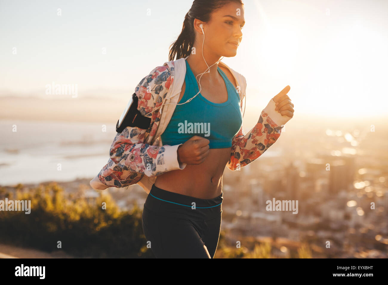 Schuss von überzeugt junge Läufer in der Sportswear auf Morgenlauf. Frau mit hellem Sonnenlicht morgens joggen. Stockfoto