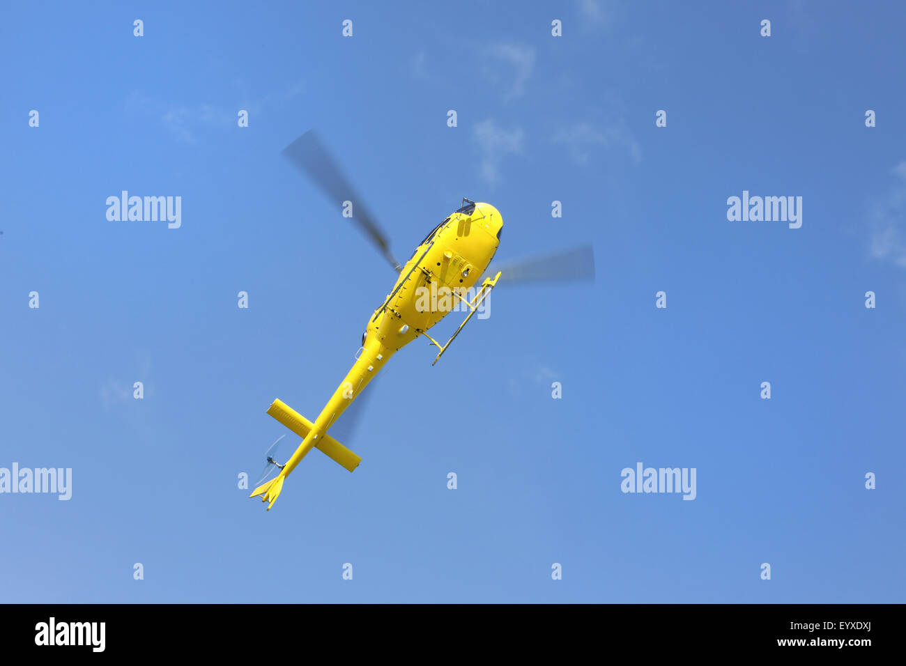 Hubschrauber-Rettung, gelbe Hubschrauber in der Luft während des Fluges auf blauen Himmel, Ansicht von unten. Alle Logos und Text entfernt. Stockfoto