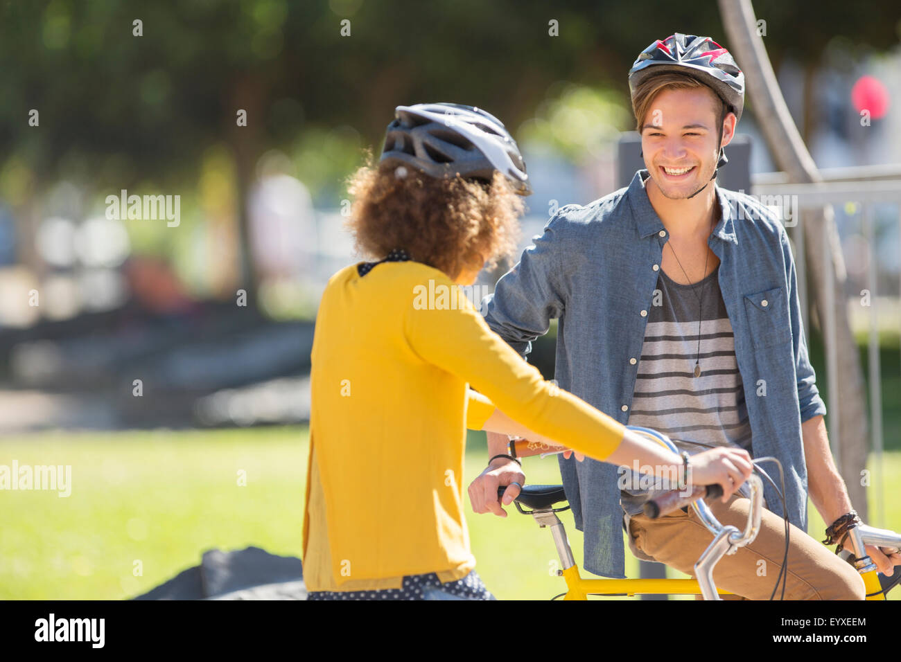 Mann und Frau mit Fahrrädern, Helmen und sprechen im park Stockfoto