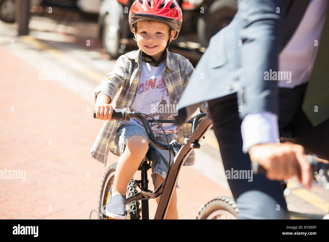 Porträt, lächelnde junge Reiten Fahrräder an sonnigen Straße Stockfoto