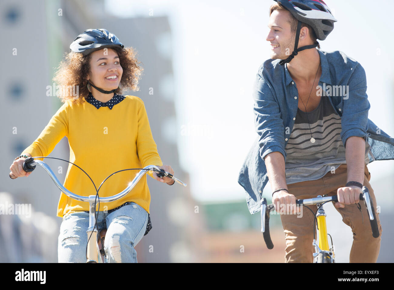 Junges Paar mit Helmen auf Fahrrädern in Stadt Stockfoto