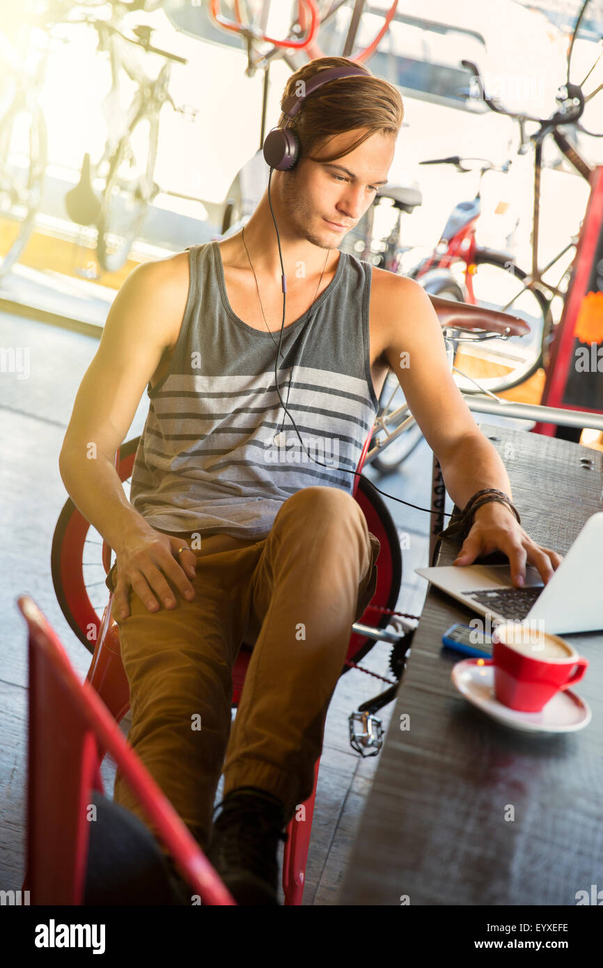 Mann mit Kopfhörer am Laptop im café Stockfoto
