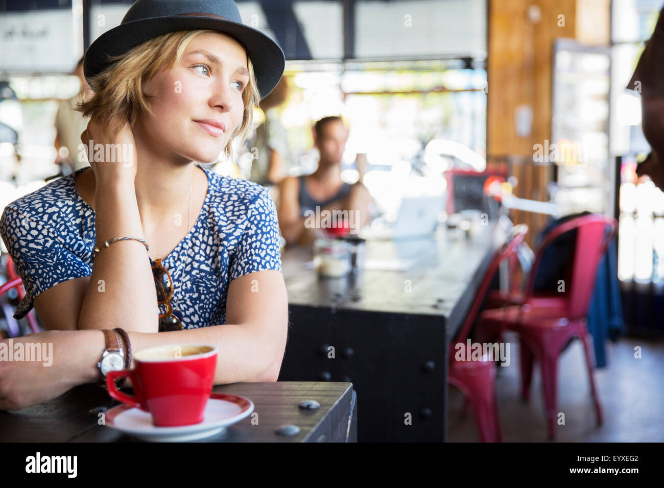 Nachdenkliche Frau mit Hut mit Kaffee im Café wegschauen Stockfoto