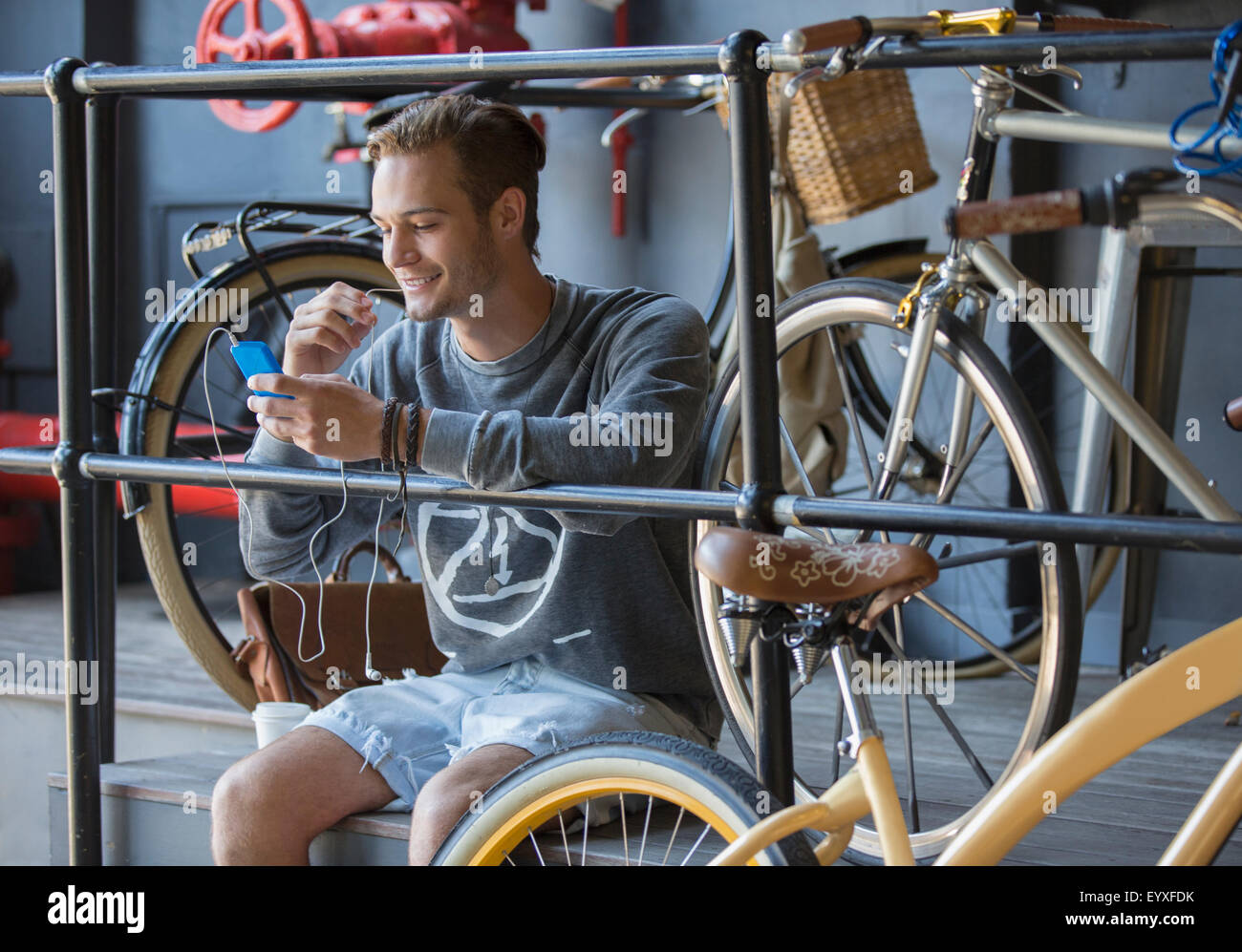 Junger Mann SMS mit Handy in der Nähe von Fahrrädern an Reling Stockfoto
