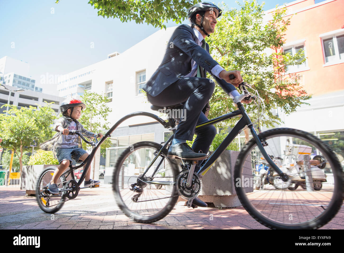 Vater der Geschäftsmann im Anzug mit Tandem-Fahrrad mit Sohn auf städtischen Bürgersteig Stockfoto