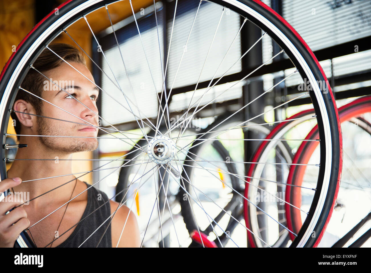 Junger Mann Prüfung Speichen Rad im Fahrradshop Stockfoto