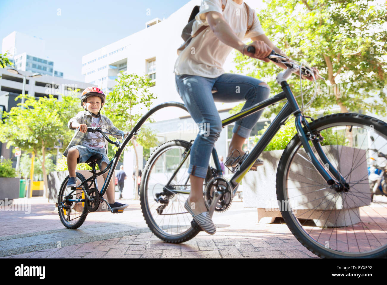 Sohn im Helm mit Tandem-Fahrrad mit Mutter im Stadtpark Stockfoto