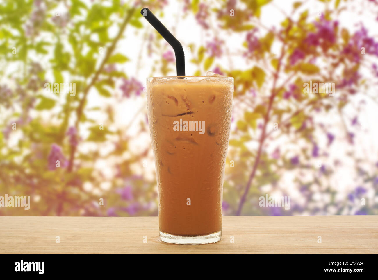 Eistee Milch auf Holz mit süßen Blumen und Hintergrund weichzeichnen Stockfoto